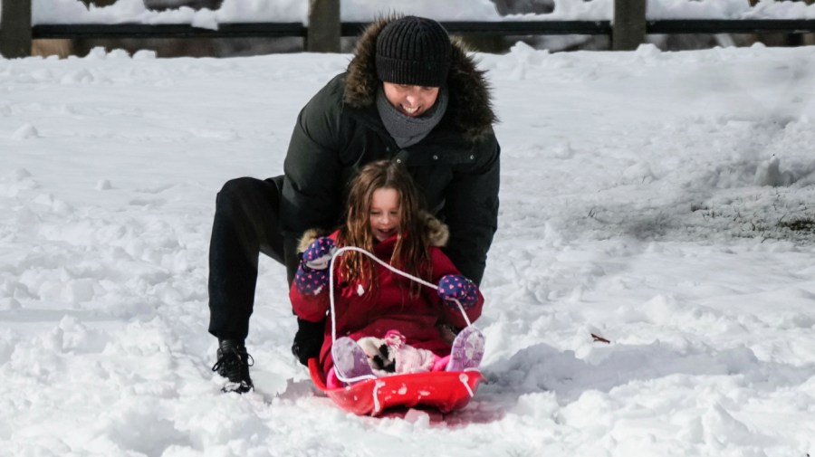 A woman plays with a child that is sledding in New York's Central Park Tuesday, Feb. 13, 2024.