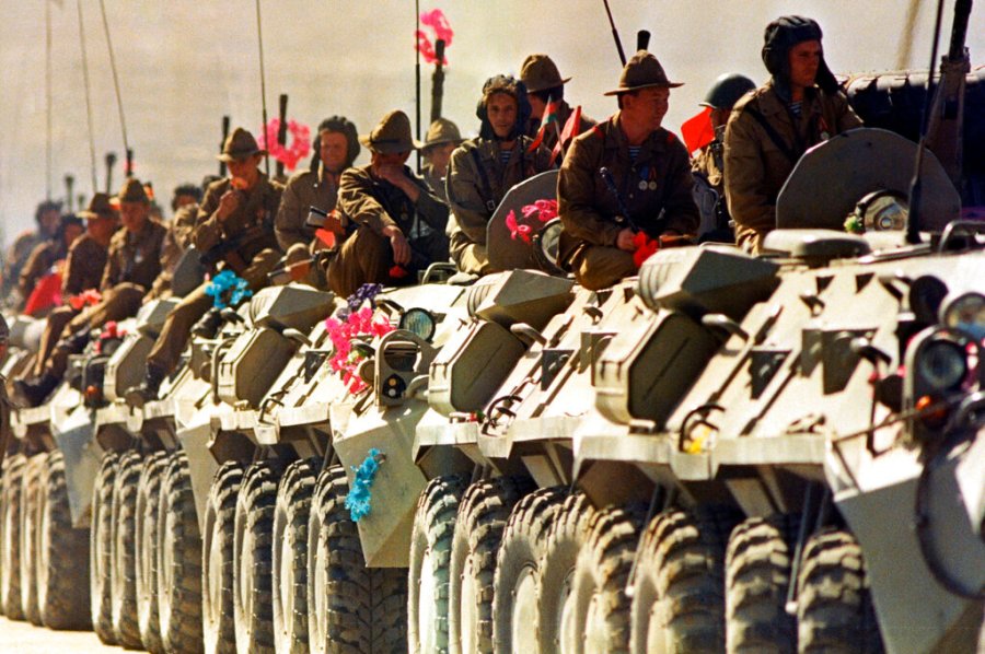 Soviet soldiers ride on top of their armored vehicles.