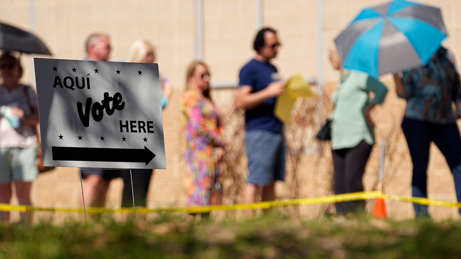 Voters use umbrellas to beat the heat as they wait in line at a polling site, Tuesday, March 5, 2024, in San Antonio.