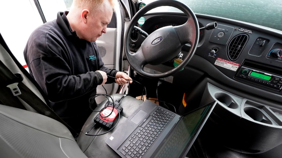 Brian Hohmann, mechanic and owner of Accurate Automotive, in Burlington, Mass., attaches a diagnostics scan tool, center left, to a vehicle and a laptop computer, below, Tuesday, Feb. 1, 2022, in Burlington.