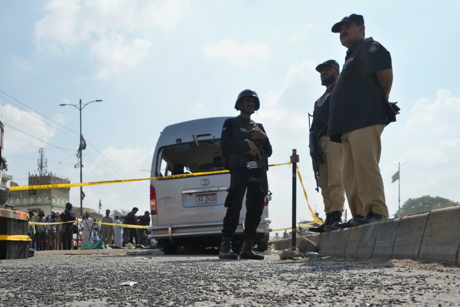 CORRECTS DATE - Police officers stand guard at the site of a suicide attack in Karachi, Pakistan, Friday, April 19, 2024. Five Japanese nationals traveling in a van narrowly escaped a suicide attack when a suicide bomber detonated his explosive-laden vest near their vehicle in Pakistan's port city of Karachi on Friday, wounding three passers-by, police said. (AP Photo/Fareed Khan)