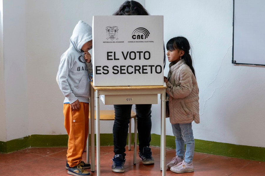Children stand by a voter marking questions on the ballot of a referendum proposed by President Daniel Noboa to endorse new security measures aimed at crack down on criminal gangs fueling escalating violence in Quito, Ecuador, Sunday, April 21, 2024. (AP Photo/Dolores Ochoa)