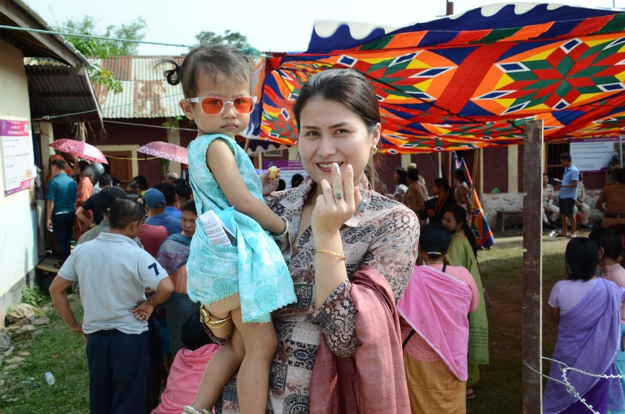 A woman carrying a child poses after casting her vote during a re-polling in Imphal West District, Manipur, India, Monday, April 22, 2024. Voters at some polling places in this northeastern state went back to the polls amid tight security on Monday after violence disrupted the vote last week. (AP Photo/Bullu Raj)