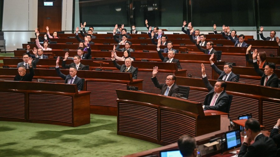 Lawmakers vote with their hands raised in the chamber of the Legislative Council.