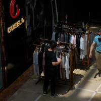 A man walks by as a vendor arranges clothes for sale outside his store at Ritan International Trade Center in Beijing on Wednesday, May 15, 2024. Data released on Friday, May 17 showed housing prices in China slumped for the first four months of the year, although factory output rose nearly 7%, as the country prepares to announce fresh measures to reinvigorate its ailing property industry. (AP Photo/Andy Wong)