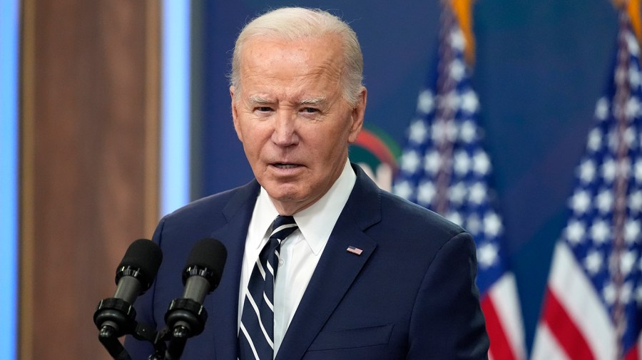 President Biden speaks in front of American flags.