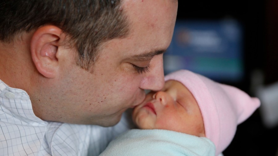 In this Thursday, May 12, 2016 photo, Mark Bailey kisses his newborn daughter Ellie Bailey after blood was collected at Community Hospital North in Indianapolis.