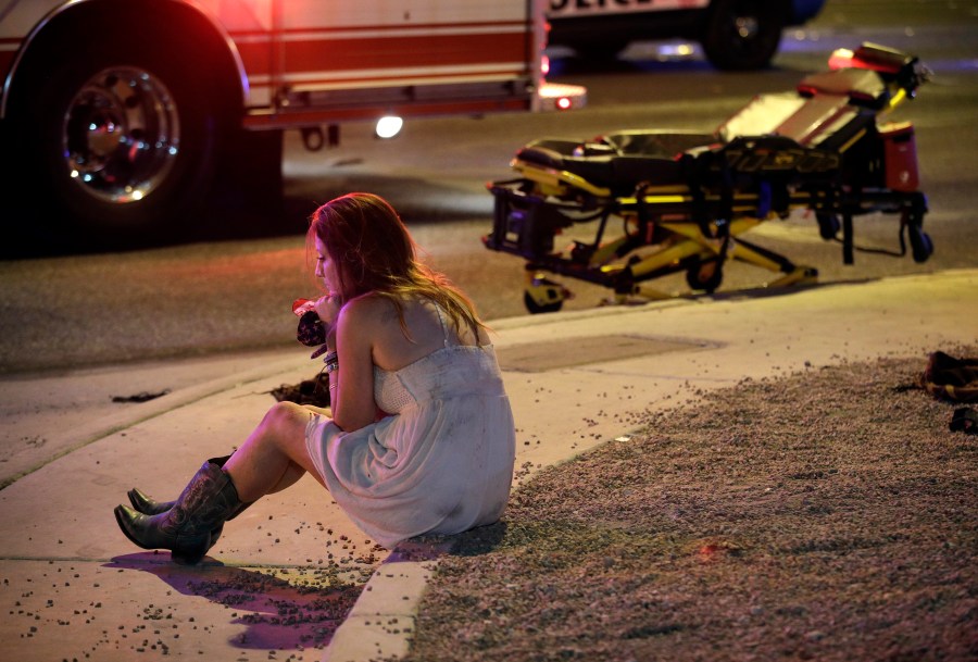 FILE - A woman sits on a curb at the scene of a shooting outside a music festival on the Las Vegas Strip in Las Vegas on Oct. 2, 2017. The Supreme Court has struck down a Trump-era ban on bump stocks, a gun accessory that allows semiautomatic weapons to fire rapidly like machine guns. They were used in the deadliest mass shooting in modern U.S. history. The high court found the Trump administration did not follow federal law when it reversed course and banned bump stocks after a gunman in Las Vegas attacked a country music festival with assault rifles in 2017.(AP Photo/John Locher, File)