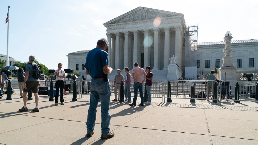 People stand in front of the Supreme Court.