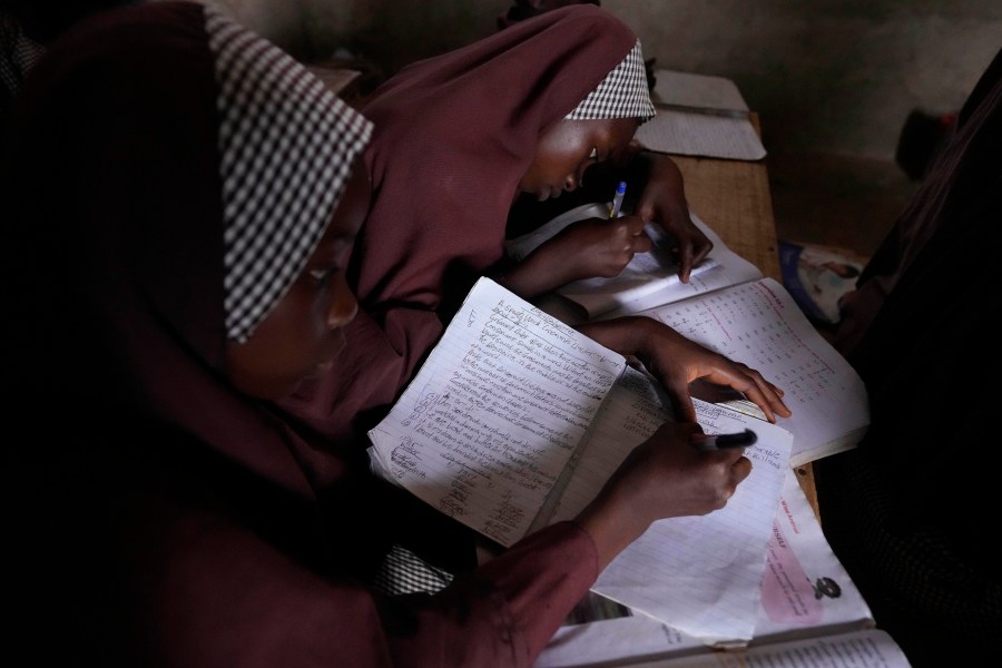 Students of Excellent Moral School attend a lesson in a dimly lit classroom in Ibadan, Nigeria, Tuesday, May 28, 2024. Schools like Excellent Moral operate in darkness due to zero grid access, depriving students of essential tools like computers. (AP Photo/Sunday Alamba)