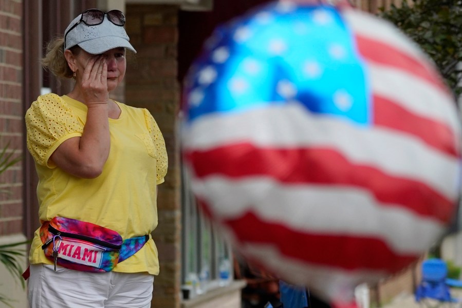 FILE - A woman wipes away tears after a mass shooting at an Independence Day parade that left seven people dead and dozens wounded, in the Chicago suburb Highland Park, July 4, 2022. Violence and mass shootings often surge in the summer months, especially around the Fourth of July, historically one of the deadliest days each year. (AP Photo/Nam Y. Huh, File)