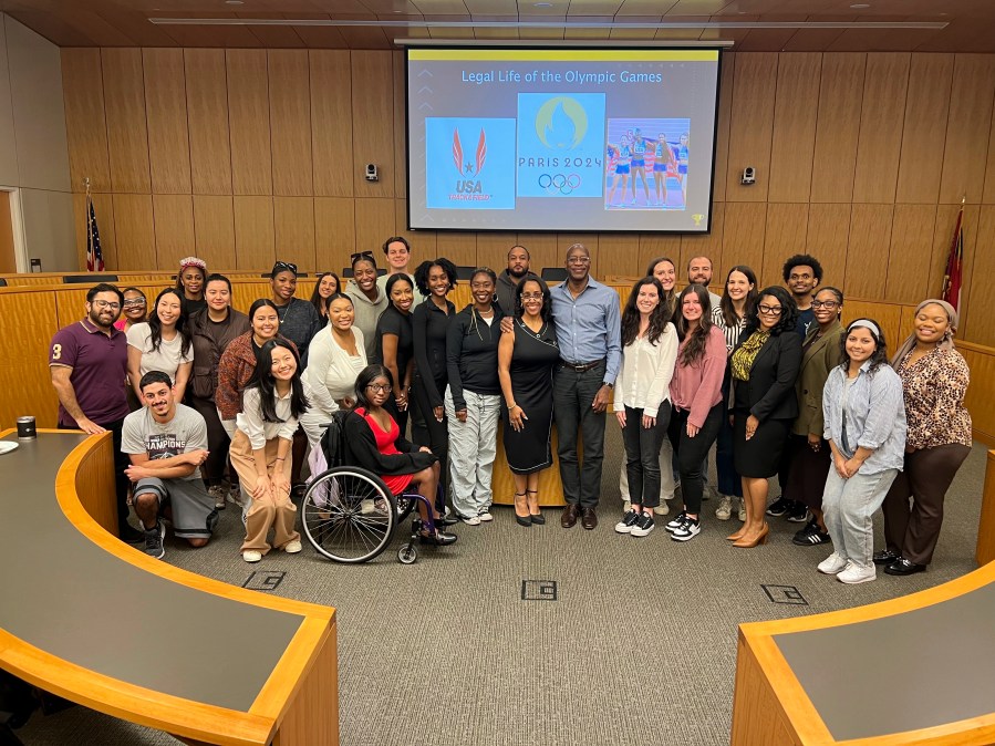 This image released by Georgia State University shows law professor Moraima “Mo” Ivory, center, left, posing with Olympian Edwin Moses, center, right, and her Legal Life class at Georgia State University in Atlanta. Ivory is known for bringing celebrities like Steve Harvey and Ludacris into her law class. But now she's taking her Atlanta law students on a free trip to the Paris Olympics this summer in hopes of creating real-life teachable moments. (Haley Austin/Georgia State University via AP)