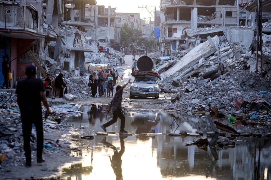 Palestinians displaced by the Israeli air and ground offensive on the Gaza Strip, walk past sewage flowing into the streets of the southern town of Khan Younis, Gaza Strip, Thursday, July 4, 2024. (AP Photo/Jehad Alshrafi)