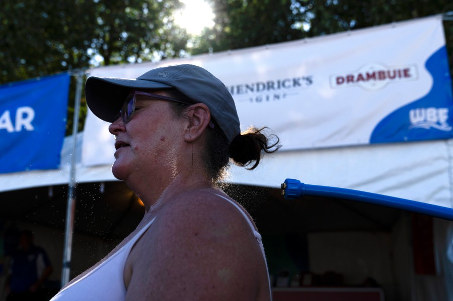 Gina Rowlett uses the mister to cool off at the Waterfront Blues Festival on Friday, July 5, 2024, in Portland, Ore. A slow-moving and potentially record-setting heat wave is spreading across the Western U.S., sending many residents in search of a cool haven from the dangerously high temperatures. (AP Photo/Jenny Kane)