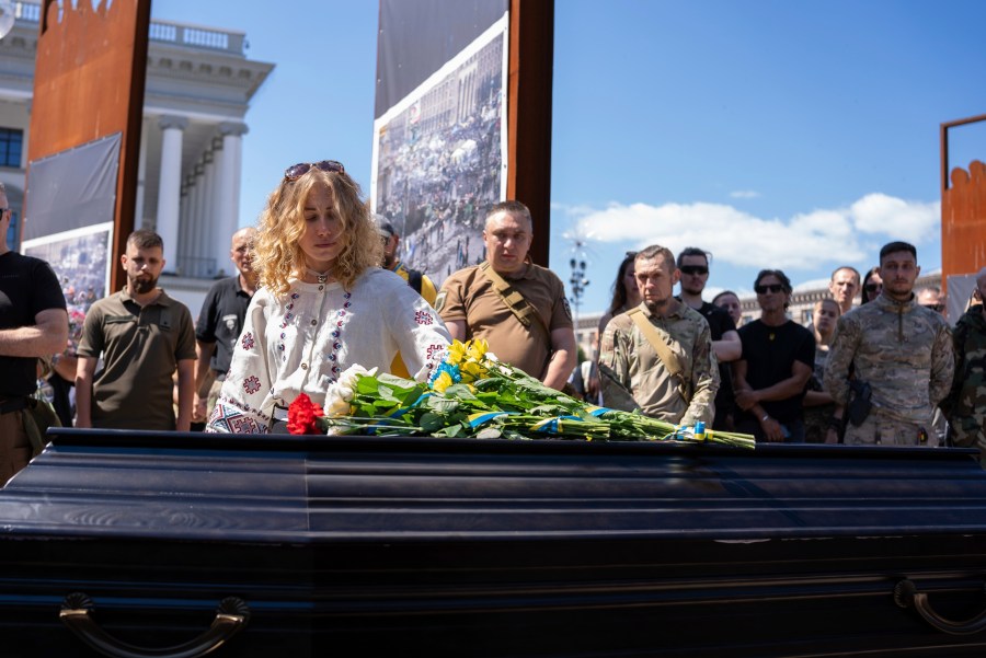 Partner of British combat medic, volunteer, Peter Fouche, 49 who was killed on June 27 during his work in East Ukraine, stands at the coffin during the funeral ceremony on the city's main square in Kyiv, Ukraine, Saturday, July 6, 2024. Peter was founder of charity organization, which provides vehicles, drones and other needs to Ukrainian servicemen. (AP Photo/Alex Babenko)