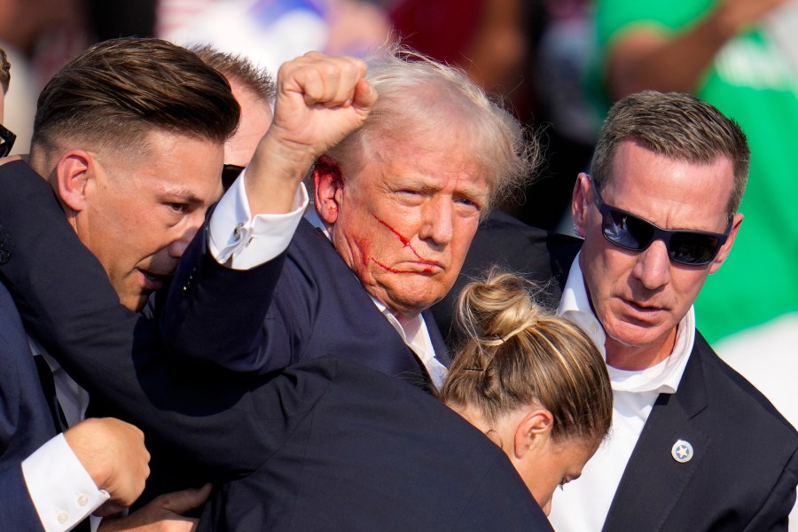 Republican presidential candidate former President Donald Trump is helped off the stage by U.S. Secret Service agents at a campaign event in Butler, Pa., on Saturday, July 13, 2024. (AP Photo/Gene J. Puskar)