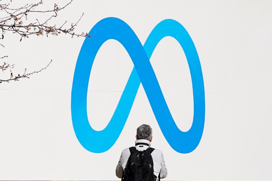 FILE - A person stands in front of a Meta sign outside of the company's headquarters in Menlo Park, Calif., March 7, 2023. (AP Photo/Jeff Chiu, File)