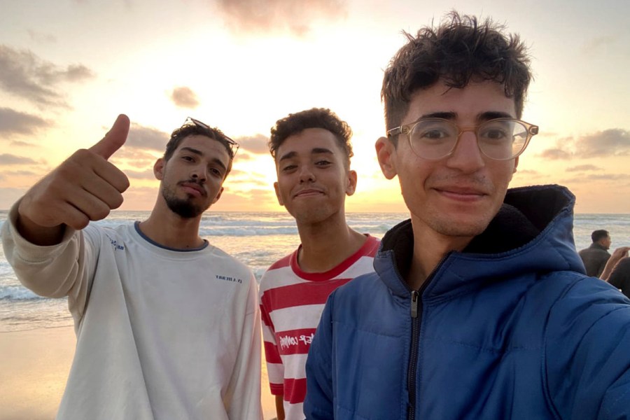 In this undated photo provided by Helmi Hirez, Mohamed (Medo) Halimy, left, and twin brothers Mohammed Hirez, center, and Helmi Hirez, right, stand on a beach in Gaza. (Helmi Hirez via AP).