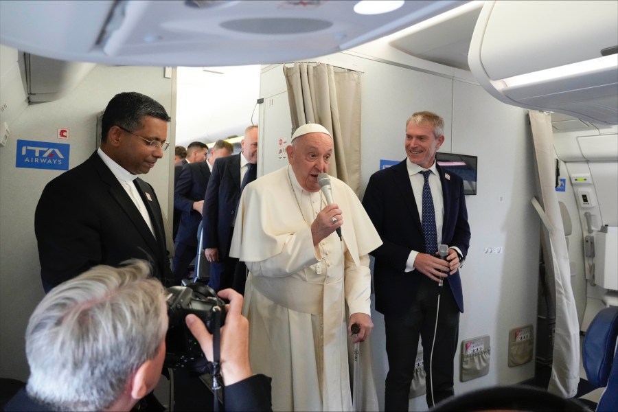 Pope Francis, center, flanked by his spokeperson Maeo Bruni, right, talks to journalists, Monday, Sept. 2, 2024, aboard the flight bound to Jakarta, Indonesia, where Francis will start his 12-day pastoral visit to Asia. Francis will clock 32,814 kilometers (20,390 miles) by air during his Sept. 2-13 visit to Indonesia, Papua New Guinea, East Timor and Singapore, far surpassing any of his previous 44 foreign trips and notching one of the longest papal trips ever, both in terms of days on the road and distances traveled. (AP Photo/Gregorio Borgia, pool)