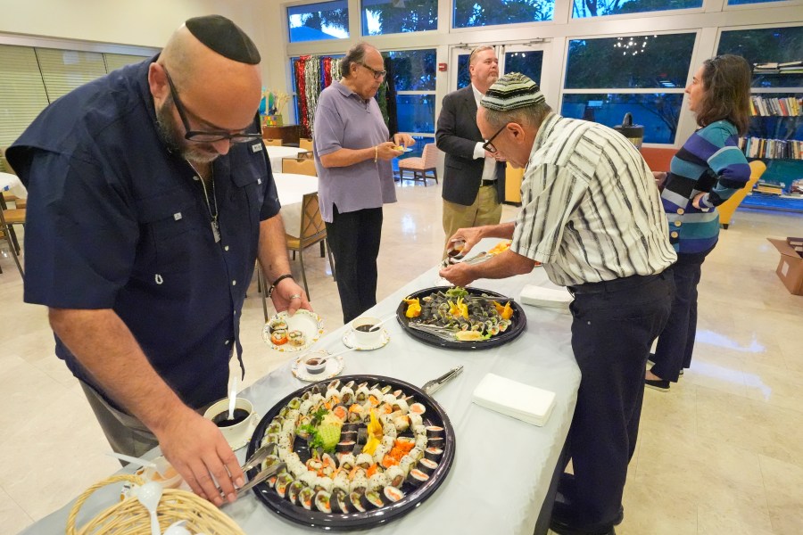 Worshipers dine on sushi after a Shabbat service, Friday, Sept. 27, 2024, at Temple Beth Sholom in Miami Beach, Fla. (AP Photo/Wilfredo Lee)