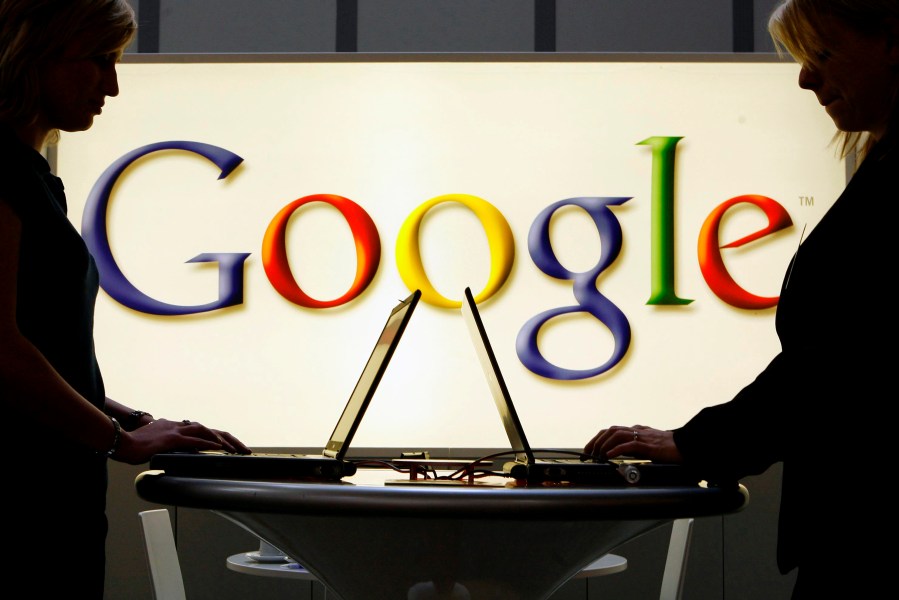 FILE - In this April 17, 2007 file photo, exhibitors work on laptop computers in front of an illuminated sign of the Google logo at the industrial fair Hannover Messe in Hanover, Germany. (AP Photo/Jens Meyer, File)