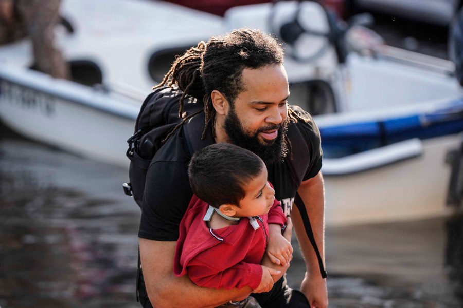 A man and child leave a rescue boat after high flood waters entered their apartment in the aftermath of Hurricane Milton, Thursday, Oct. 10, 2024, in Clearwater, Fla. (AP Photo/Mike Stewart)