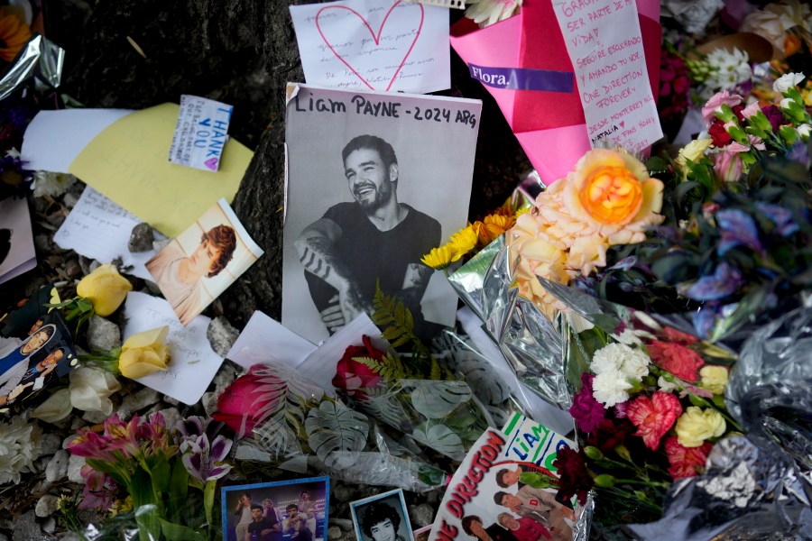 A picture of former One Direction singer Liam Payne sits surrounded by flowers and candles as fans gather outside the hotel where he was found dead after falling from a balcony in Buenos Aires, Argentina, Thursday, Oct. 17, 2024. (AP Photo/Natacha Pisarenko)