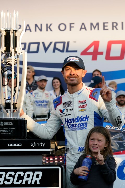 Kyle Larson poses with the trophy with his daughter Audrey, 6, after winning a NASCAR Cup Series auto race at Charlotte Motor Speedway in Concord, N.C., Sunday, Oct. 13, 2024. (AP Photo/Chuck Burton)